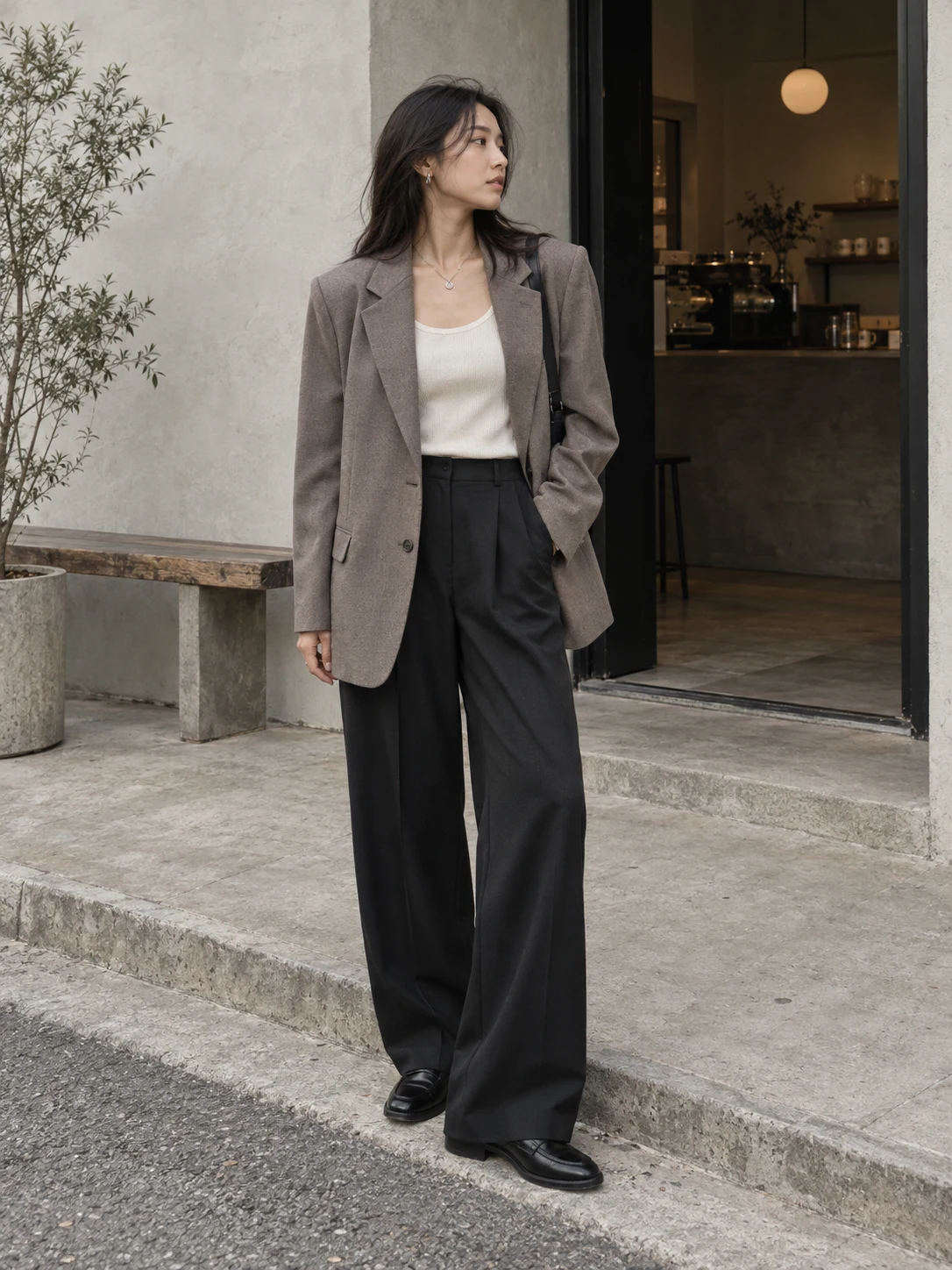An oversized taupe blazer and wide-leg black trousers outside a cafe